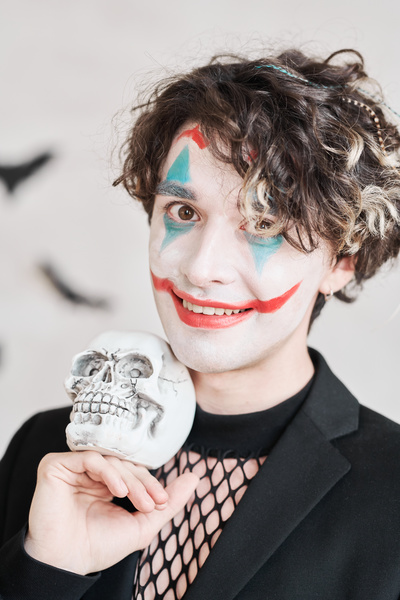 Man with Joker Makeup Holds Skull near His Face